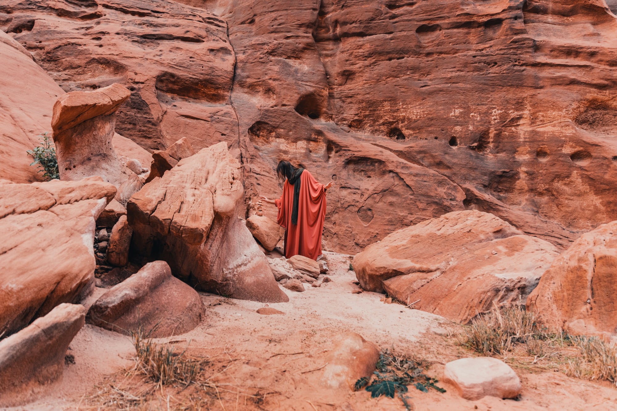 Person in a red robe standing in a rocky landscape